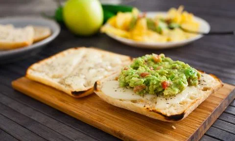 Toasted slices of square bread with warm cheese and homemade guacamole on plate Stock Photos