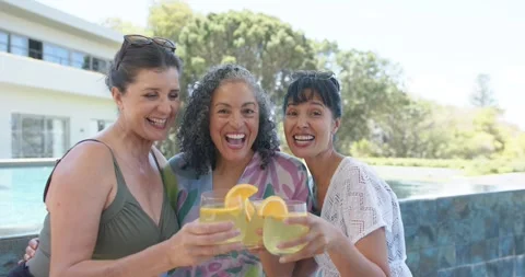 Toasting 3 friends by pool, one friend signaling and all raising glasses toward Stock Footage 340987678