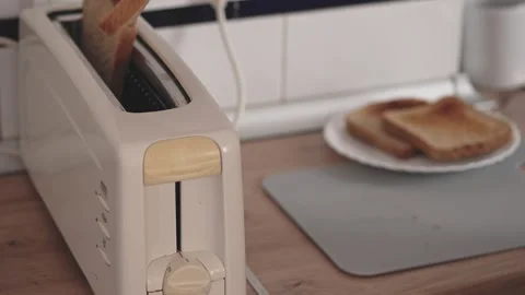 Toasting bread in a kitchen with a silver toaster on the counter around midda Stock Footage 340193452