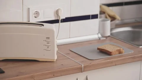 Toasting bread in a kitchen with a toaster by a sink and counter during the morn Stock Footage 338166803