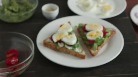 Toasts with  avocado cherry tomatoes boiling egg arugula on  plate  panning shot Stock Footage 104289759