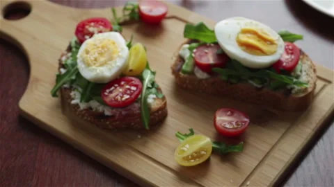 Toasts with  avocado cherry tomatoes boiling egg arugula panning shot. Stock Footage 132331407