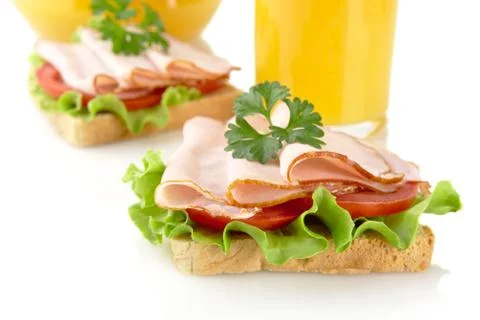 Toasts with cold cuts for breakfast with orange juice on white background Stock Photos