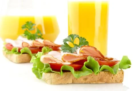 Toasts with cold cuts on lunchtime with orange juice on white background Stock Photos