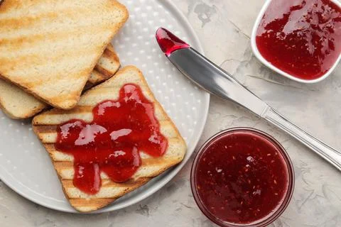 Toasts with jam. fried crispy toasts with red jam on a light concrete table. Stock Photos