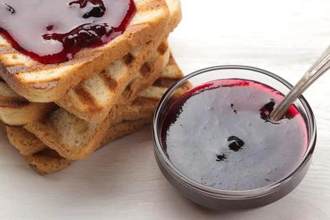 Toasts with jam. fried crispy toasts with red jam on a white wooden table. Stock Photos