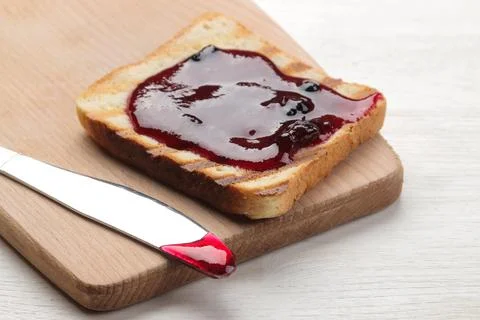 Toasts with jam. fried crispy toasts with red jam on a white wooden table. Stock Photos