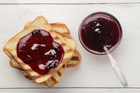 Toasts with jam. fried crispy toasts with red jam on a white wooden table. br Stock Photos