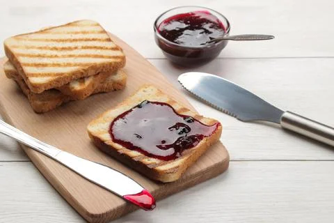 Toasts with jam. fried crispy toasts with red jam on a white wooden table. Stock Photos