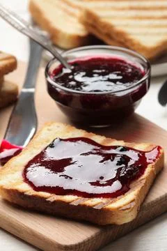Toasts with jam. fried crispy toasts with red jam on a white wooden table. br Stock Photos