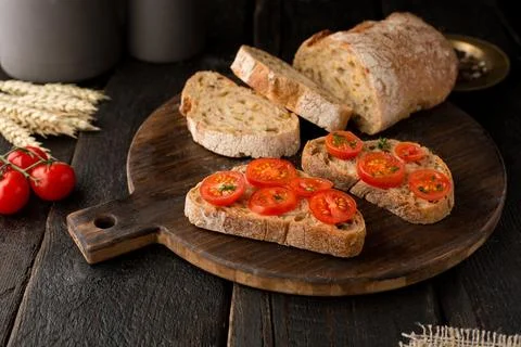 Toasts with tomatoes and bread on a board on a wooden background Stock Photos