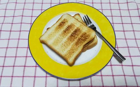Toasts in a white dish with fork on patterned tablecloth Stock Photos