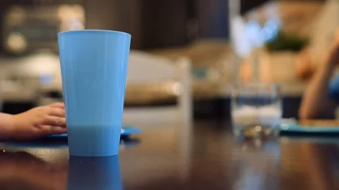 Toddler accidentally spills cup of milk on the table and mother wipes it up Stock Footage