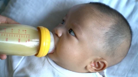 Toddler baby boy drinking milk from bottle mom hand feed Stock Footage