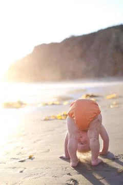 Toddler bending over on beach Stock Photos