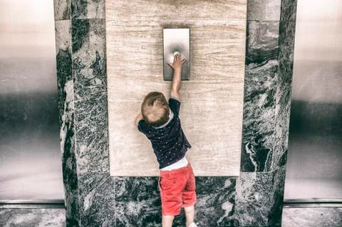 Toddler boy calling elevator button Stock Photos