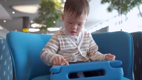 Toddler boy child using tablet pc playing game while waiting for his flight Stockbeeldmateriaal 103198856