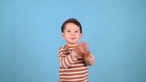 Toddler boy clap his hands. Little boy in a fashionable hat and striped sweater Stock Footage 180704400