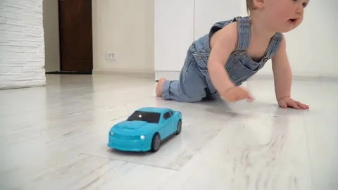 Toddler boy crawling on a light-colored wooden floor inside a home. Stock Footage 301807562
