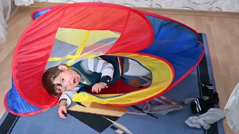 Toddler boy crawling through a tent. Funny little boy lying on the floor Stock Footage 170480551