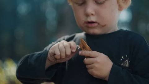 Toddler boy with dirty face cuts wood with little knife and enjoys making Stock Footage 341664218