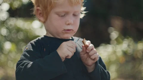 Toddler boy with dirty face cuts wood with little knife and enjoys making Stock Footage 341664596