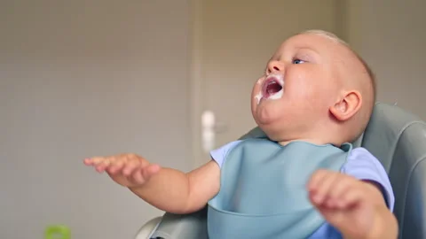 Toddler boy eats independently using a baby spoon. One and a half year old boy Stock Footage 319927989