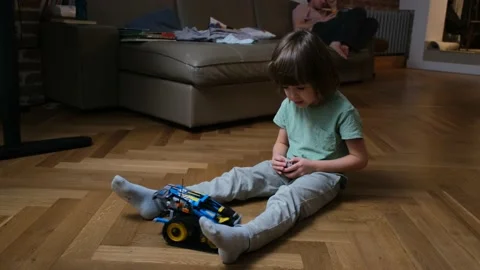 Toddler boy examines remote control toy vehicle on floor Video stock 164961652