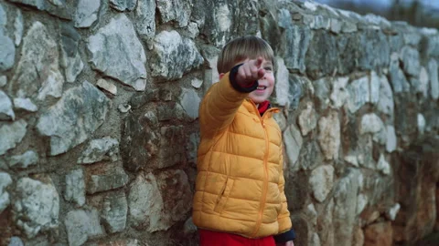 Toddler boy in front of a stone wall greets to the camera Stock Footage 178947174