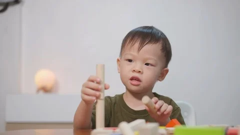 Toddler boy having fun playing with wooden building block toys indoor  Stockbeeldmateriaal 103788821