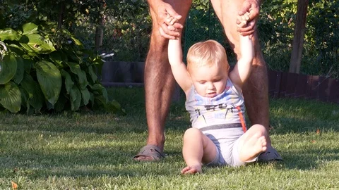 Toddler boy learning to walk on grass in back yard Stock Footage 128711791
