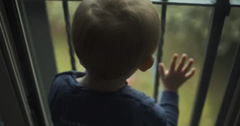 Toddler boy looking out the window. shot in slow motion Stock Footage 99400377