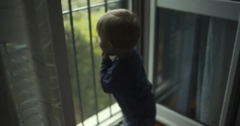 Toddler boy looking out the window. shot in slow motion Stock Footage 99400597
