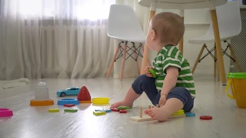 Toddler boy is playing with educational geometric sorter at home. Early developm Video stock 297198802