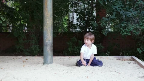 Toddler boy is playing in sandbox, dressed in white t-shirt. Stock-Footage 282804170