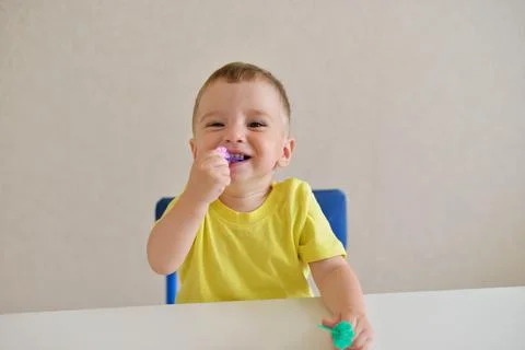 Toddler boy plays constructor while sitting at a white table. educational gam Stock Photos