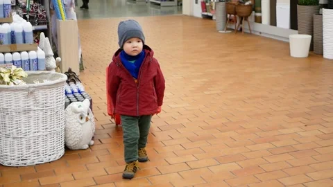 Toddler boy pulls shopping cart and looking around walking in hardware store. Stock Footage 153430178