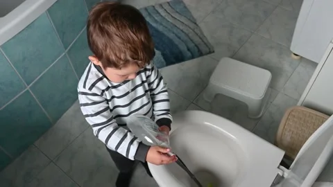 Toddler boy shows how he washes the toilet with a liquid soap. Stock Footage 171665640