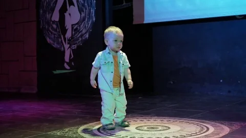 Toddler boy standing in the middle of the scene and is floodlit. Cute child Stock Footage 76466906