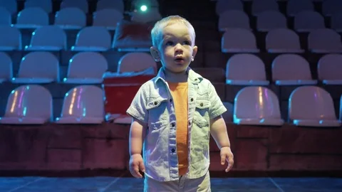 Toddler boy standing in the middle of the scene and is floodlit. Cute child Stock Footage 76467157