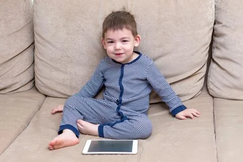 Toddler boy is using a tablet on a couch Stock Photos