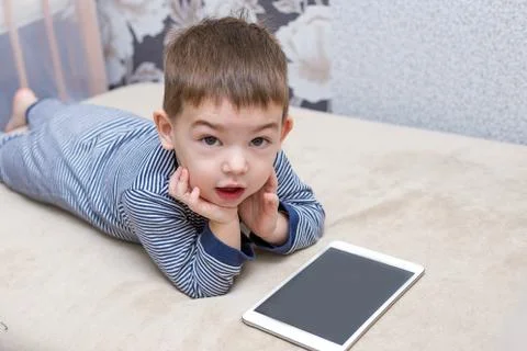 Toddler boy is using a tablet on a couch Stock Photos
