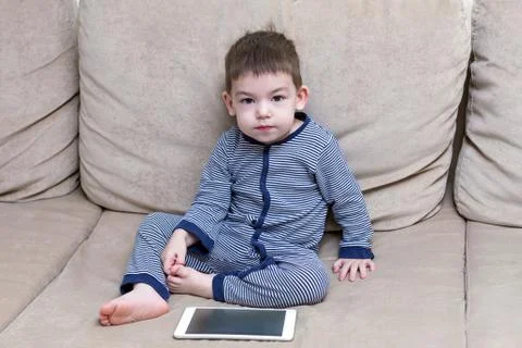 Toddler boy is using a tablet on a couch Stock Photos