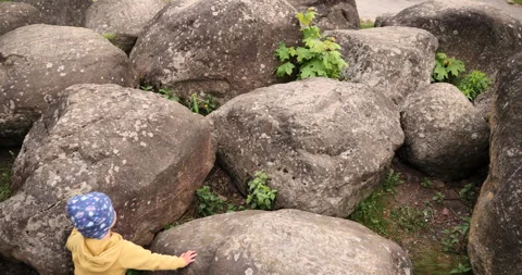 Toddler boy wanders between large boulders. rocks are like rocks to a spirit boy 動画素材 243381569