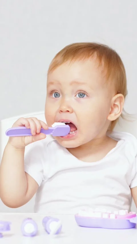 Toddler brushing teeth learning dental hygiene with a toy doctor kit while Stock Footage 341285639