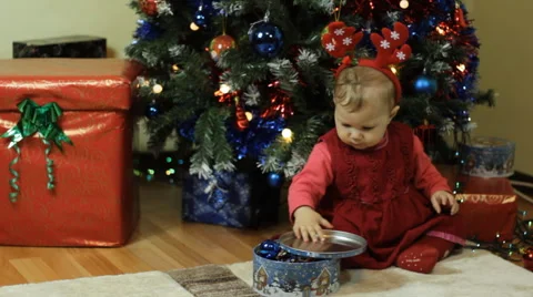 Toddler with candy box next ot a Christmas tree Stock Footage 57647570