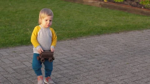 Toddler carries a rusty toy train carriage Stock Footage 310945461