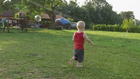 Toddler Chase Bubbles Distance - 4k - Slow motion Stock-Footage 70447982