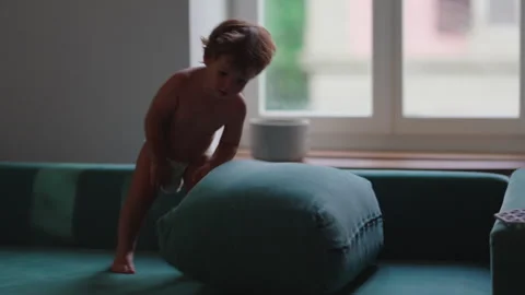 Toddler climbing cushion and falling onto sofa during indoor play, celebrat.. Stock Footage 340449533