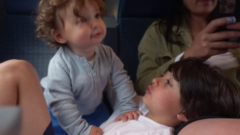 Toddler climbing onto older sibling during passenger train journey, playful.. Stock Footage 338122061